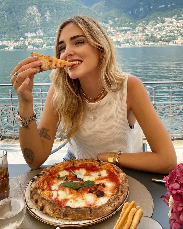 a woman sitting at a table with a pizza in front of her