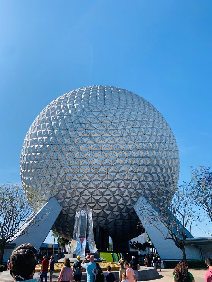 people are walking around in front of the spaceship shaped building at epcote disney world