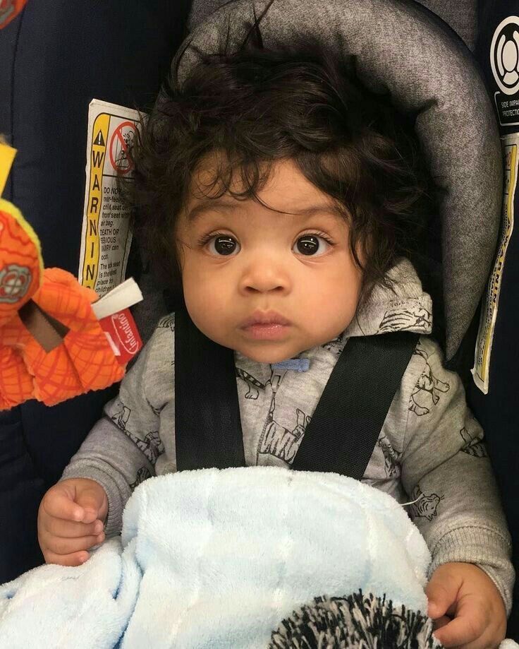 a baby sitting in a car seat with a stuffed animal on it's back