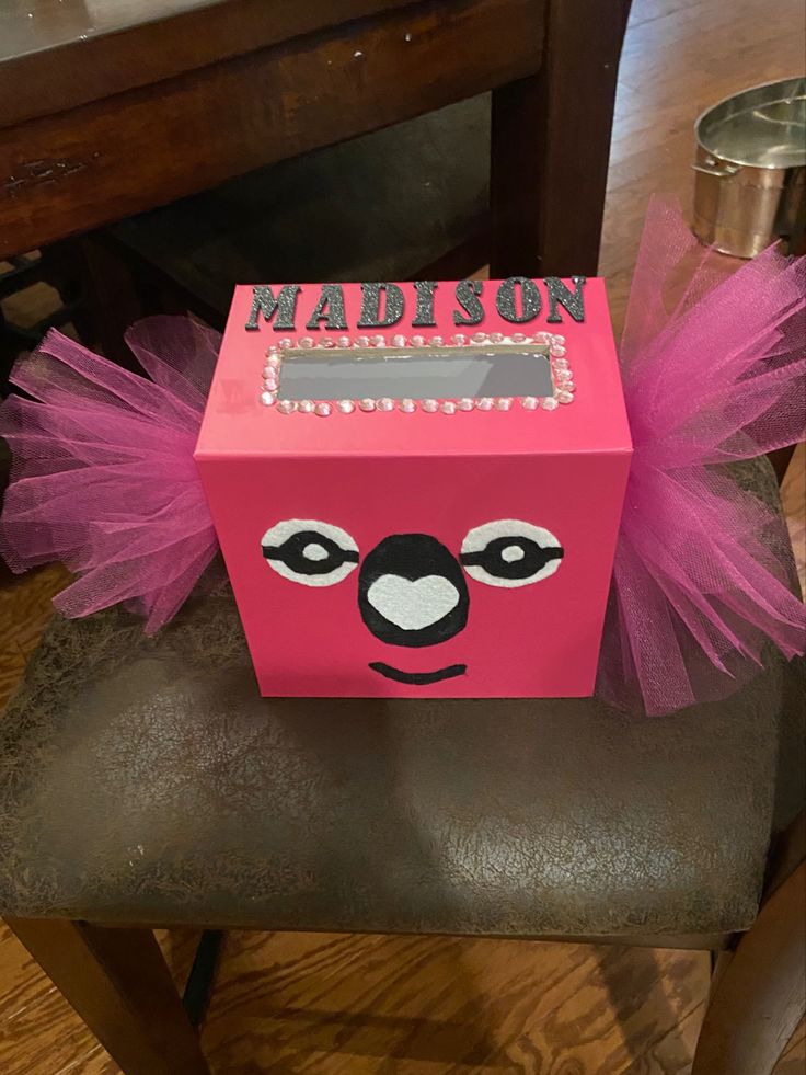 a pink box with a koala's face on it sitting on top of a chair