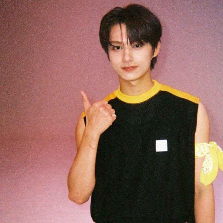 a young man in a black and yellow shirt giving the peace sign