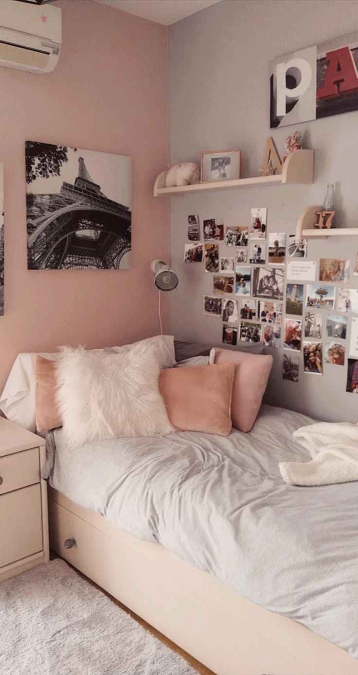 a bedroom with pink walls and pictures on the wall above the bed, along with white fluffy pillows