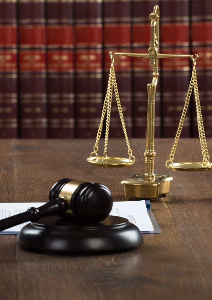 a judge's scale and gavel on a table in front of law books