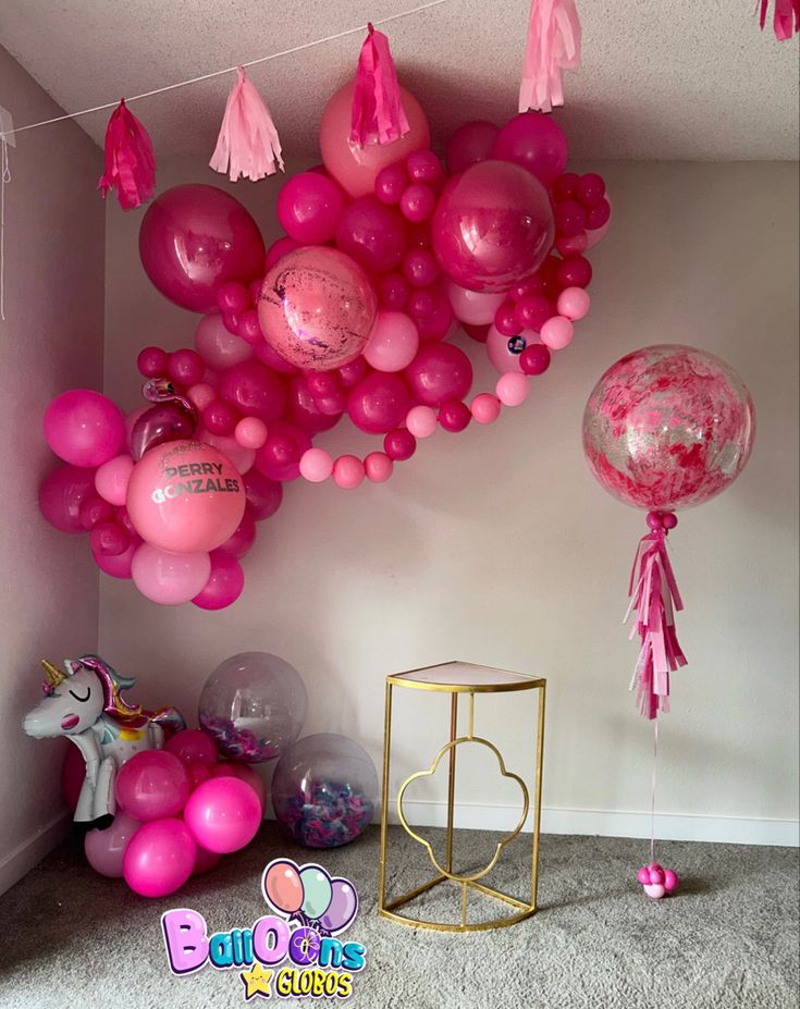 pink balloons and tassels are hanging from the ceiling in a room with carpet