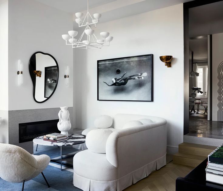 a living room filled with white furniture and a painting hanging on the wall over a fire place