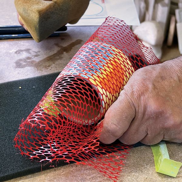 a man is working on something with red mesh