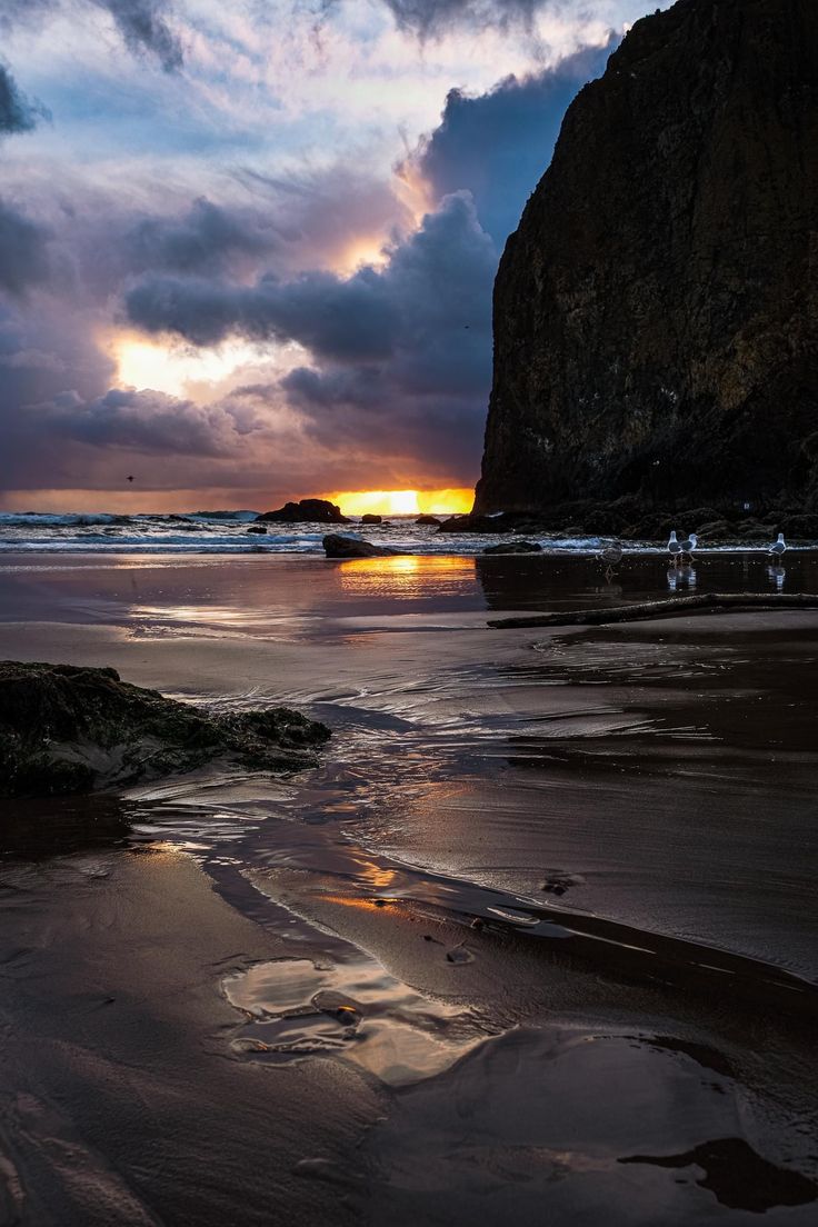 the sun is setting at the beach with waves coming in