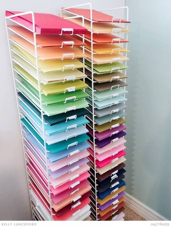 a large stack of file folders sitting on top of a white shelf next to a wall