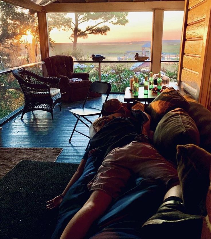 two people laying on the back of a couch in front of a large window with an ocean view