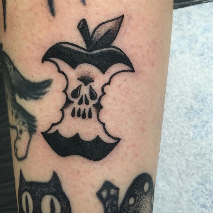 an apple and two cats tattoo on the left leg, with one skull in the middle