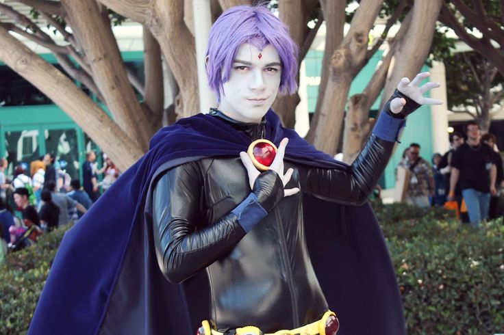 a man dressed up in costume and holding a red object while standing next to trees