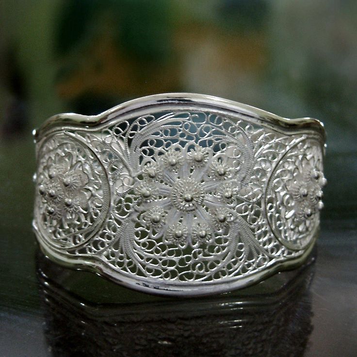 Yuli conjures the splendor of Eden in this exquisite sterling cuff. Graceful and beautiful the bracelet features a trio of fine filigree flowers amid leaves and tendrils. .925 Sterling silver Filigree Bangle, Garden Romantic, Silver Wrap Ring, Filigree Bracelet, Wide Cuff Bracelets, Filigree Jewelry, Floral Bracelet, Romantic Lace, Custom Tumbler