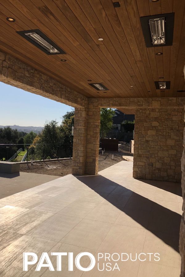 an outdoor patio area with stone walls and wood ceilinging, overlooking the valley in the distance