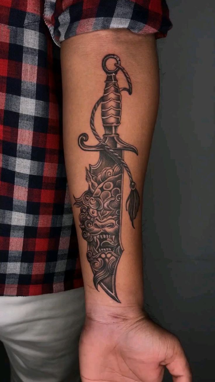 a man with a tattoo on his arm holding a knife in the shape of a skull