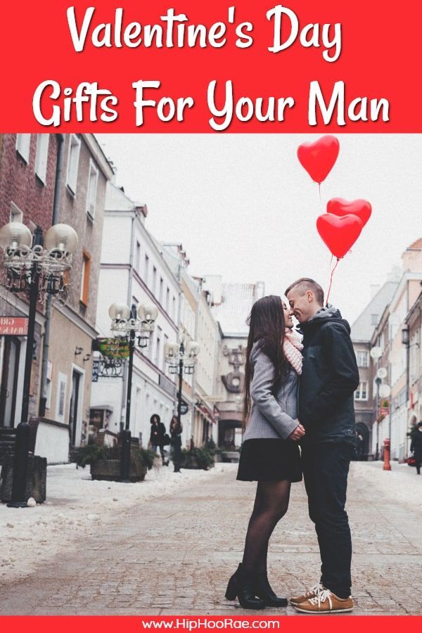 a man and woman kissing on the street with red heart balloons