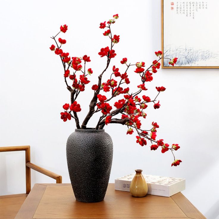 a vase filled with red flowers on top of a wooden table