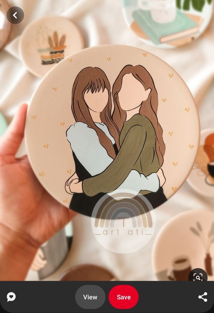 someone holding up a paper plate with an image of two women hugging each other on it