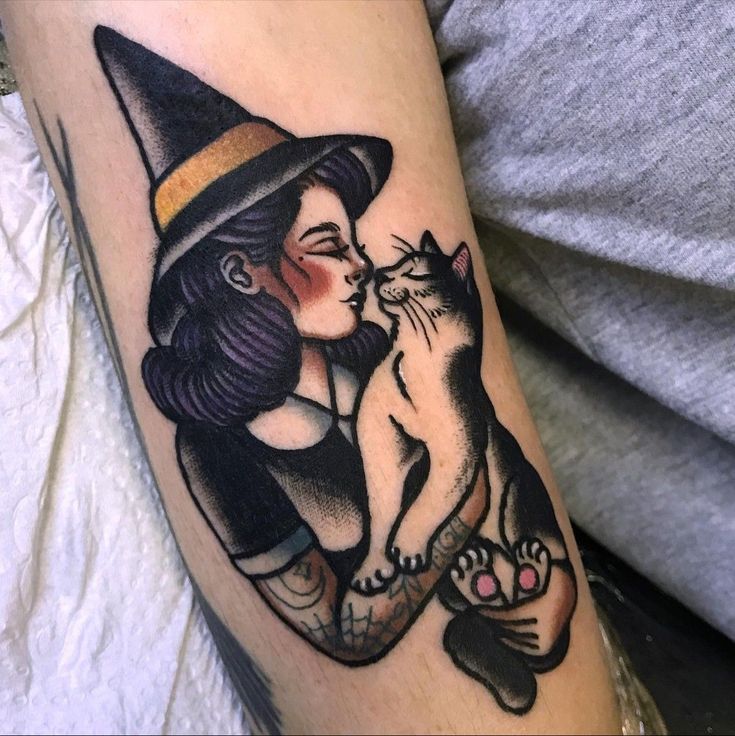 a woman with a cat on her arm is wearing a witches hat and holding a kitten