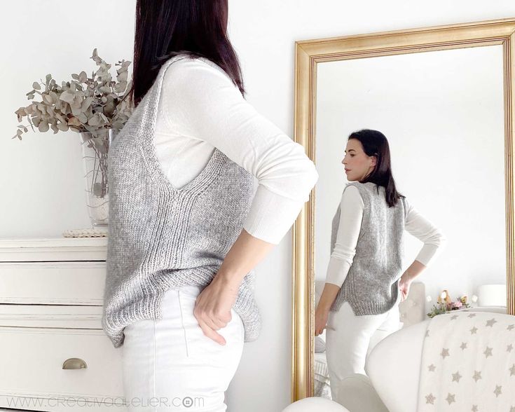 a woman standing in front of a mirror with her back to the camera, looking at herself