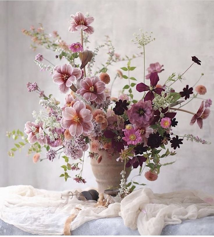 a vase filled with lots of flowers on top of a table