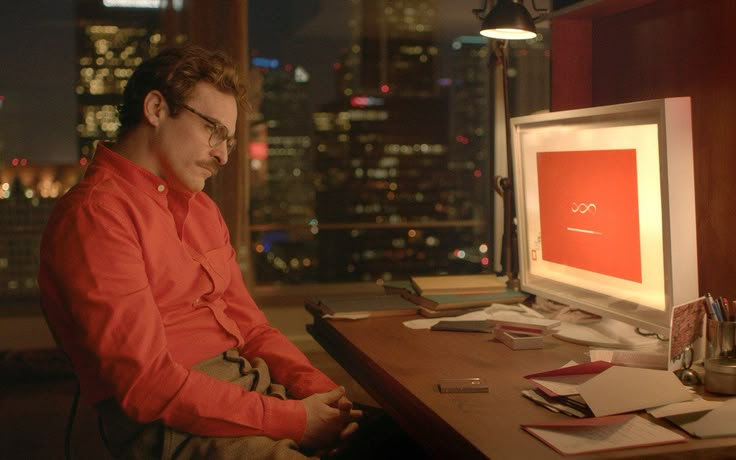 a man sitting at a desk in front of a computer monitor