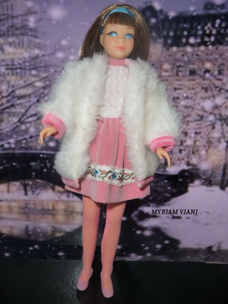 the doll is wearing a pink dress and white fur coat