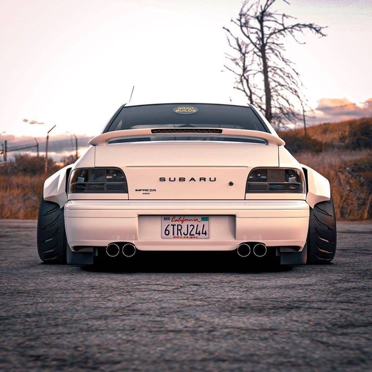 the rear end of a white car parked in a parking lot