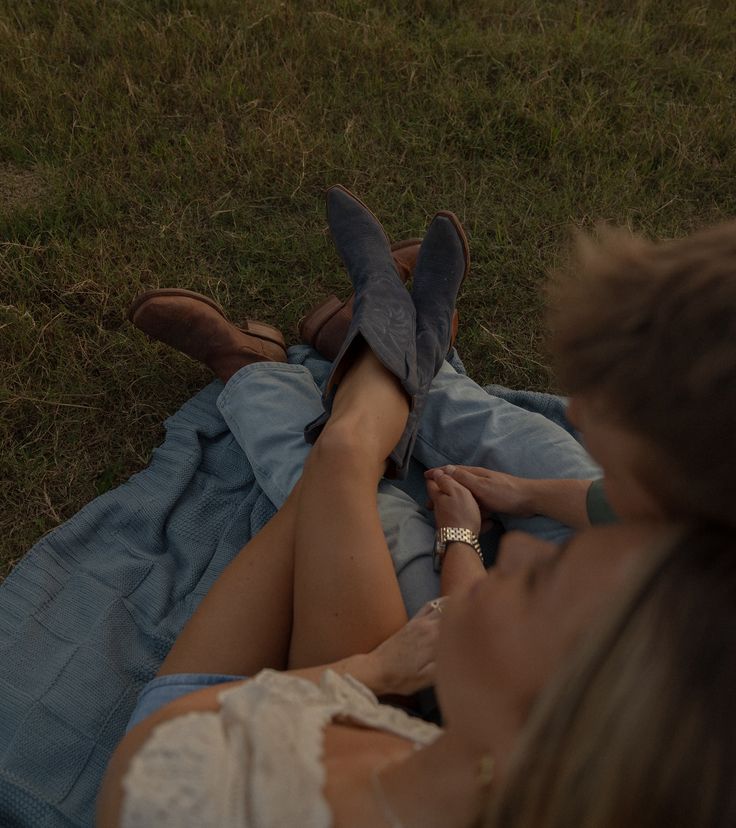 two people laying in the grass with their feet on each other's legs,