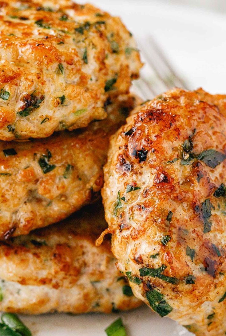 three crab cakes stacked on top of each other with herbs and seasoning around them