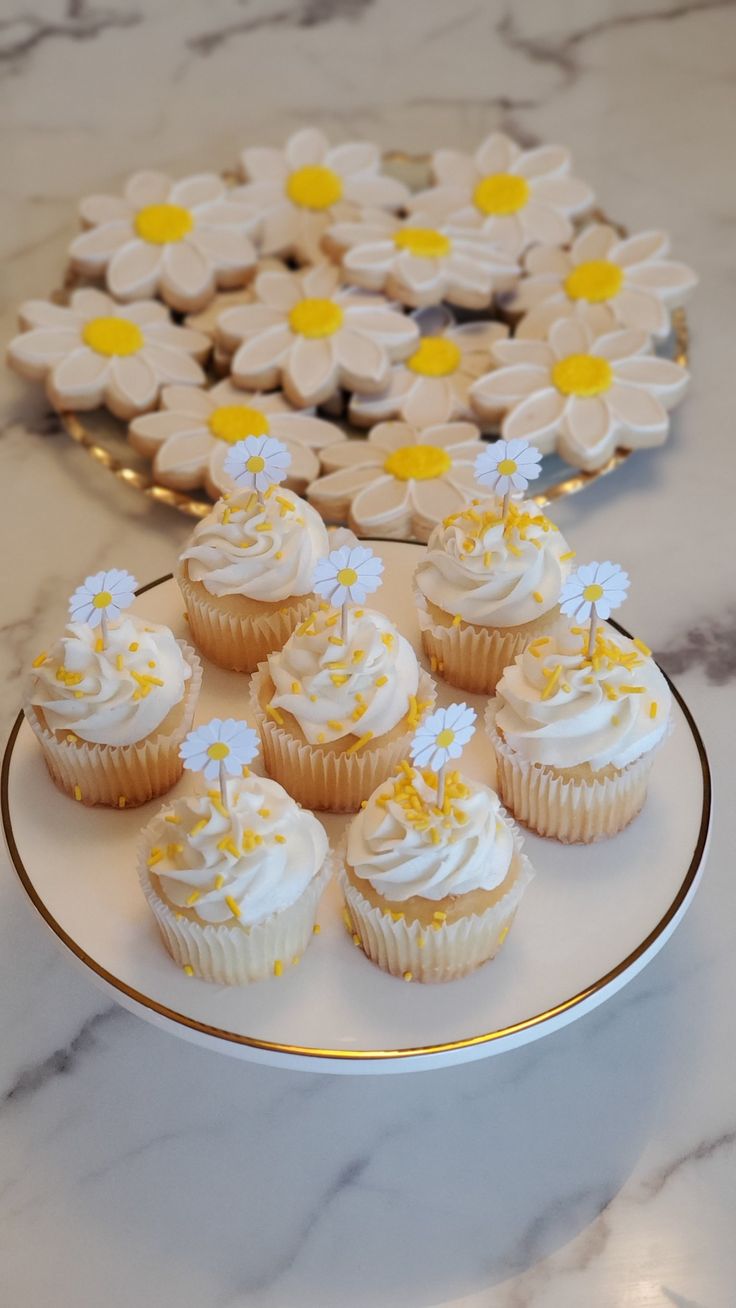 cupcakes with white frosting and yellow sprinkles on a plate