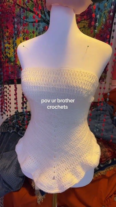 a white crocheted top on a mannequin with the words pov ur brother crochets