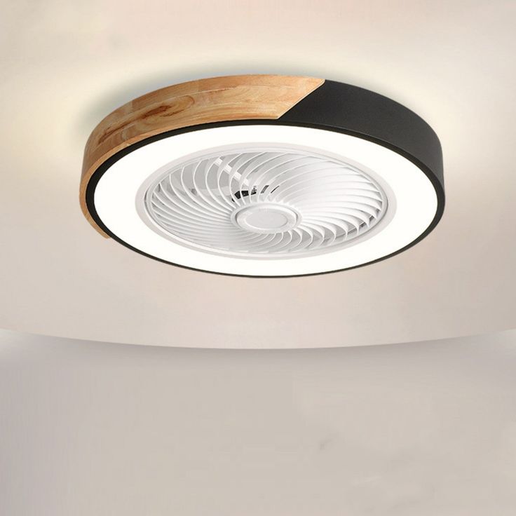 a white and black circular light fixture with wood trim on the ceiling in an empty room