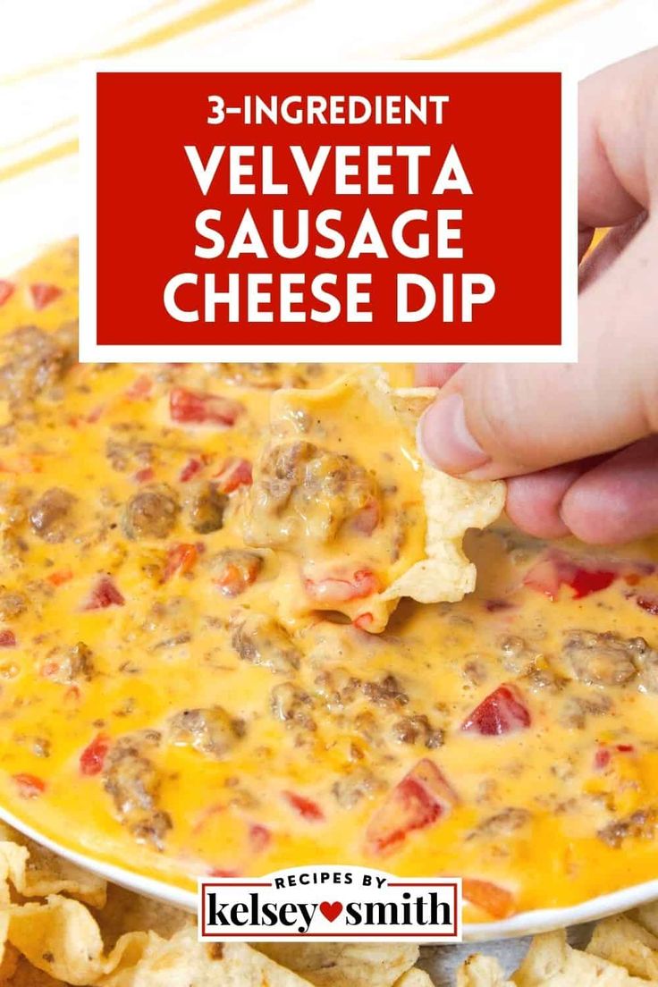 someone dipping cheese into a cheesy dip in a white bowl with tortilla chips