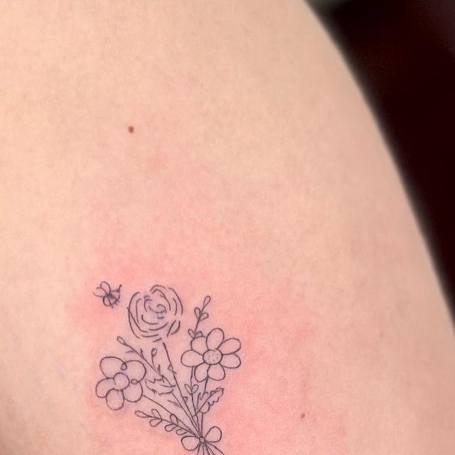 a small flower tattoo on the back of a woman's shoulder