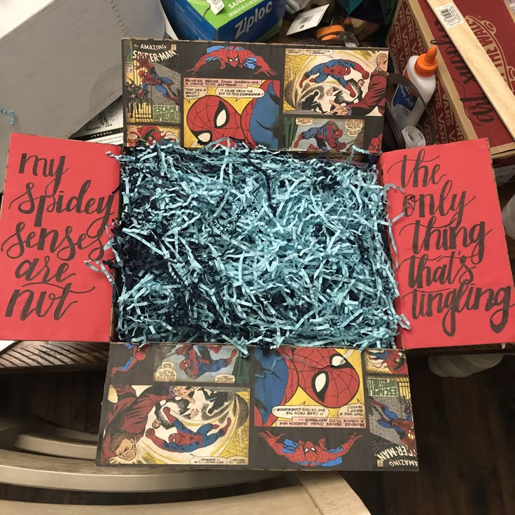 some kind of box that is filled with blue shredded paper and spider - man stickers