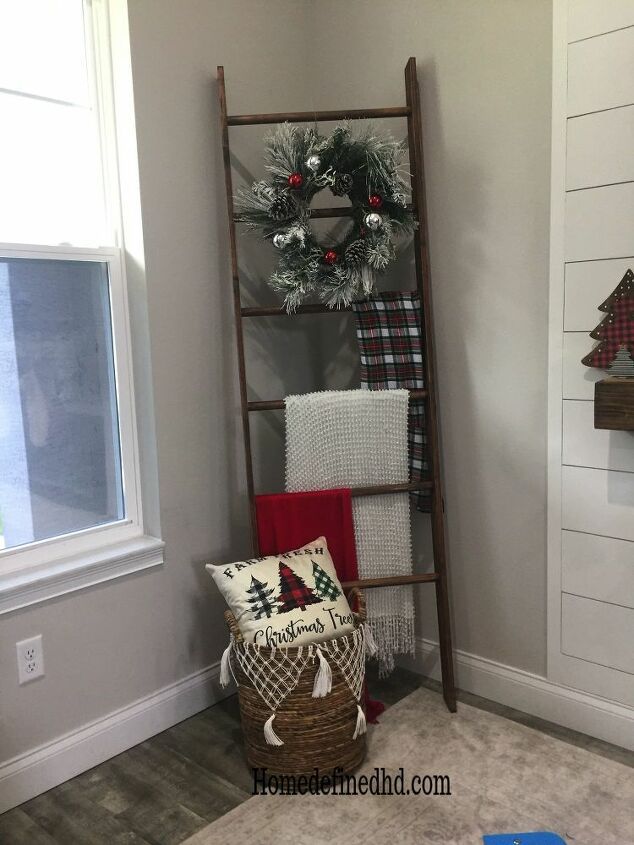 a ladder in the corner of a room with christmas decorations on it and a wreath