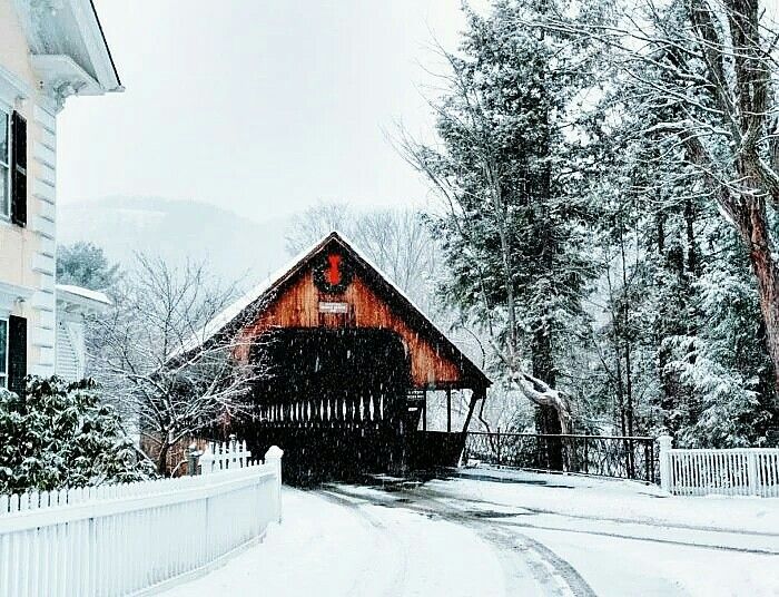 a snow covered road with a house in the background and trees on both sides,