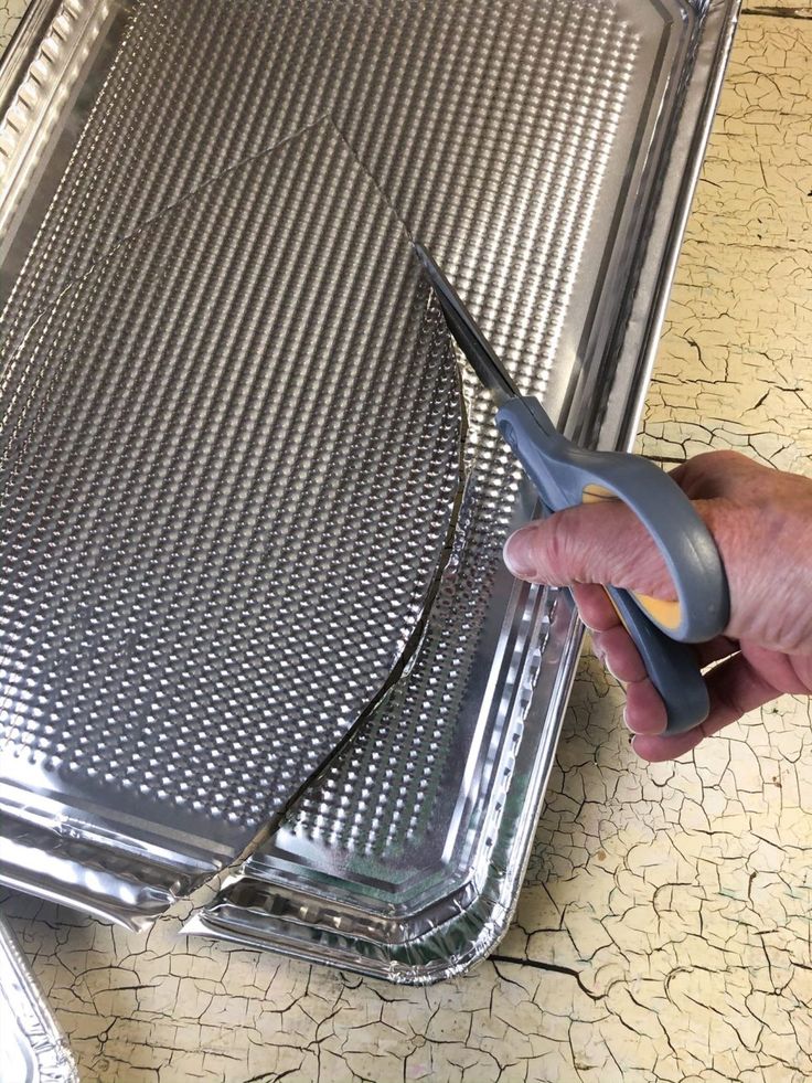 a person holding a pair of scissors near a piece of luggage on the ground with cracks in it