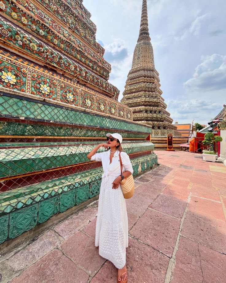 a woman in a white dress and straw hat standing next to a large green building