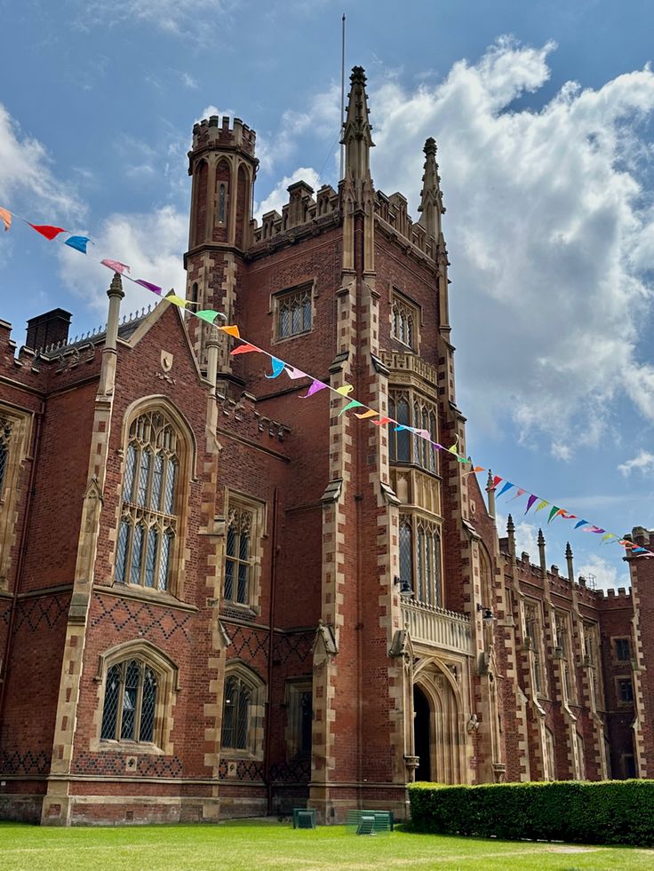 an old brick building with flags flying in the wind on a sunny day at university