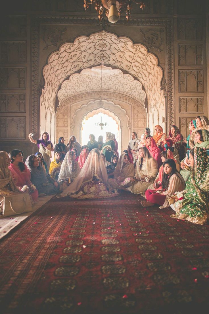 a group of people sitting on top of a red rug in front of a doorway