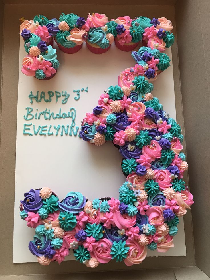 a birthday cake in the shape of the number five with cupcakes and flowers