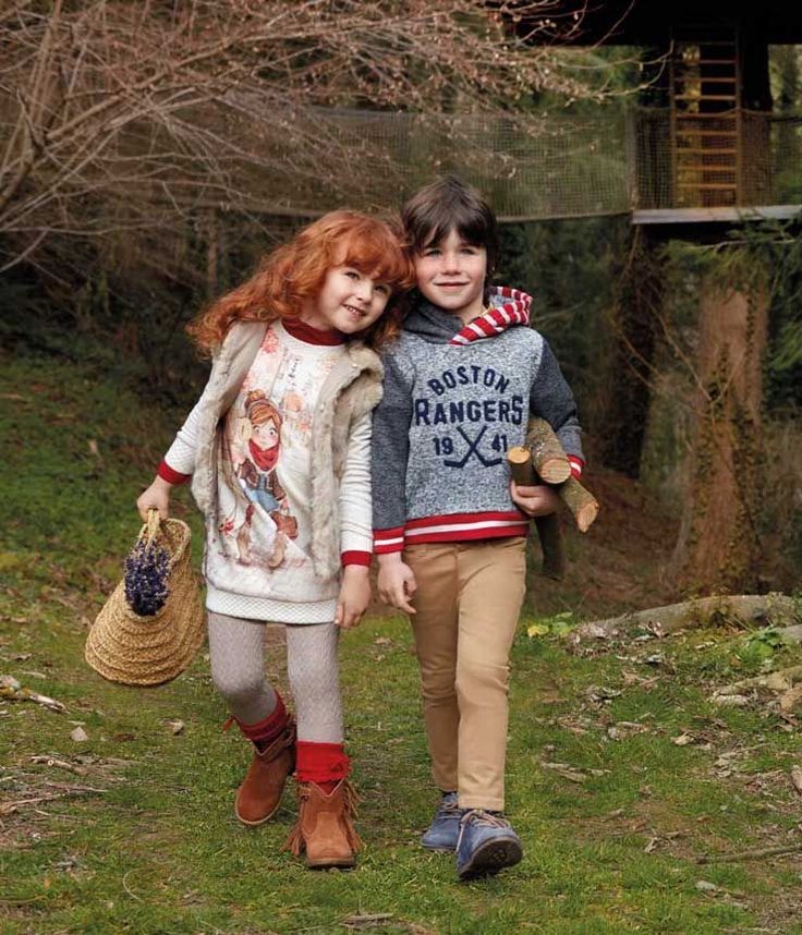 two young children are walking in the grass