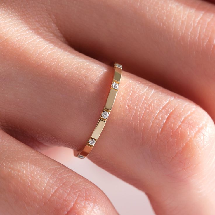 a woman's hand wearing a gold ring with three diamonds on the middle finger