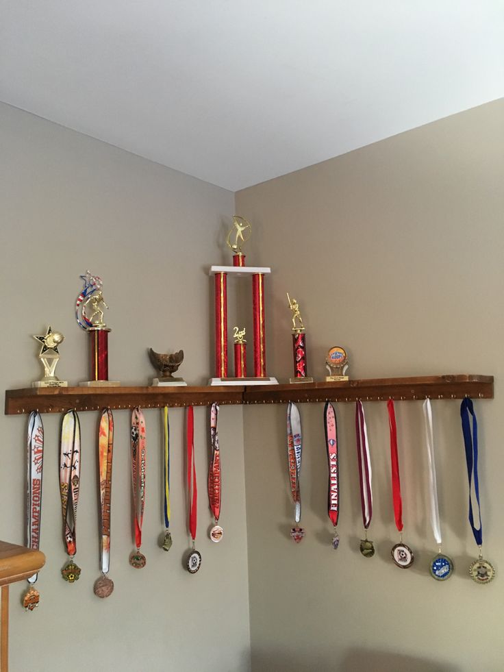 several medals are hanging on a shelf above a bed