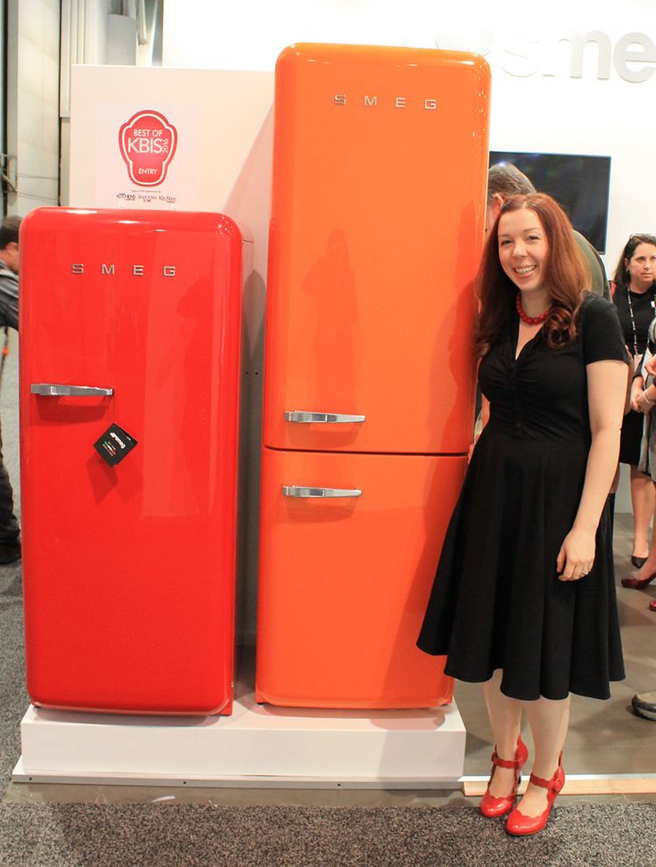 a woman standing next to an orange refrigerator