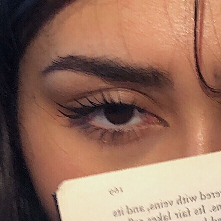 a close up of a person's eye with a book in front of her