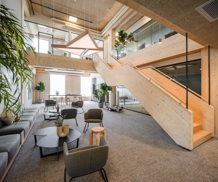 an office lobby with chairs, tables and stairs leading up to the second floor area