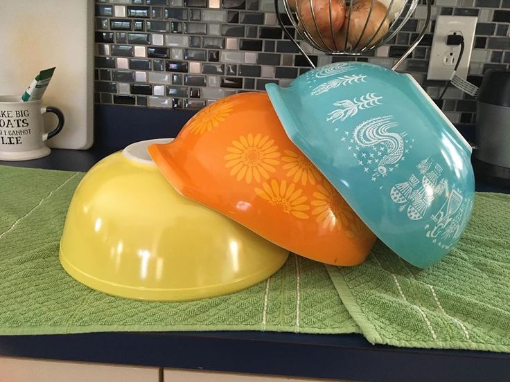 three colorful bowls sitting on top of a counter next to a blender and mixer