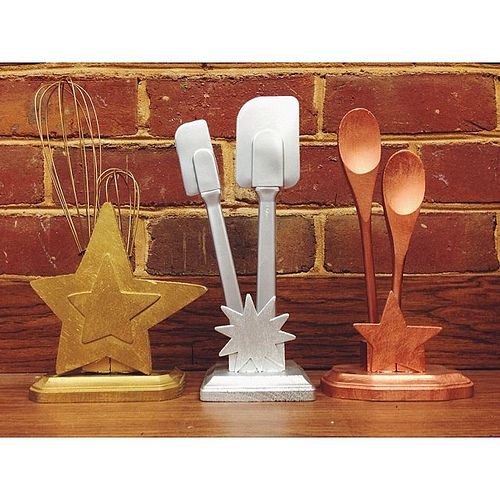 three spoons and two star shaped utensils on a wooden table next to a brick wall